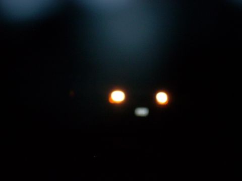 1992 Ford Bronco - The front of a vehicle is barely visible at night, with only its headlights illuminated.
