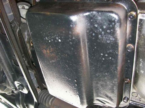 1984 Ford Bronco - Underside view of a vehicle's transmission pan, showing oil residue and mounting bolts.