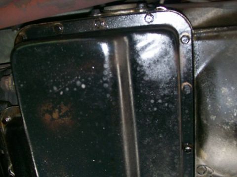 1984 Ford Bronco - Close-up view of a vehicle's transmission pan, showing bolted construction and some surface discoloration.
