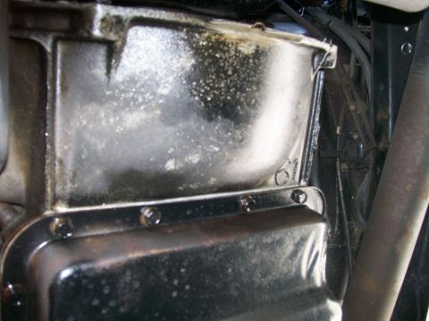 1984 Ford Bronco - Close-up of an oil pan with a casting mark, showing bolts and surrounding engine components.