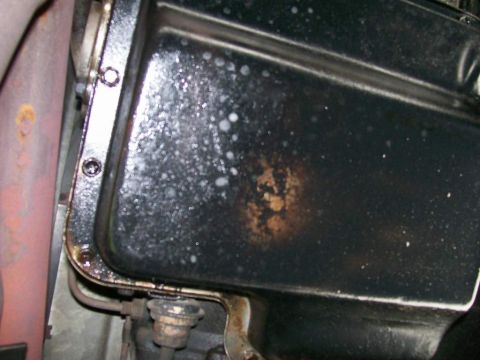 1984 Ford Bronco - Close-up view of a vehicle's transmission pan, showing signs of oil residue and rust.
