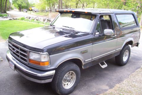 1995 Ford Bronco - This two-tone 1995 Ford Bronco is parked outside a house with trees in the background.