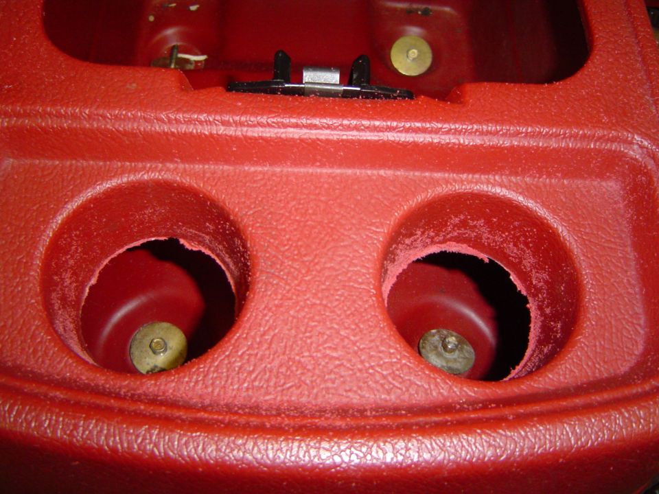 Red plastic center console with two round cupholder openings and a latch