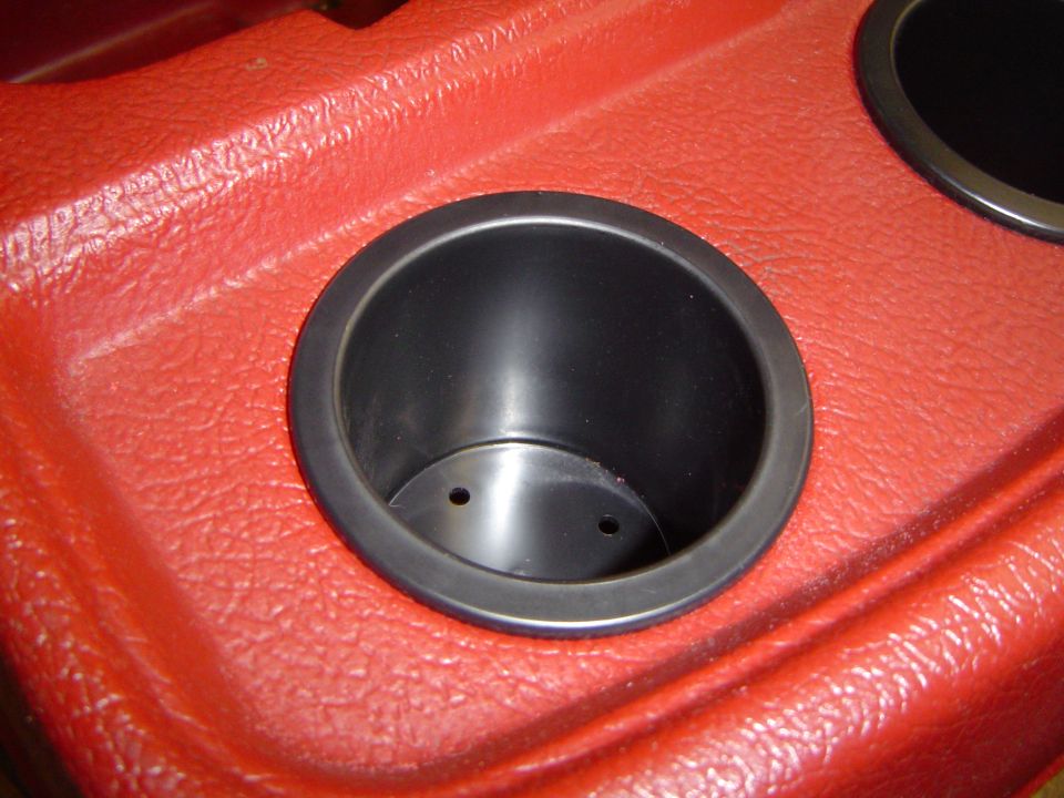 Black cup holder in a red textured vehicle console