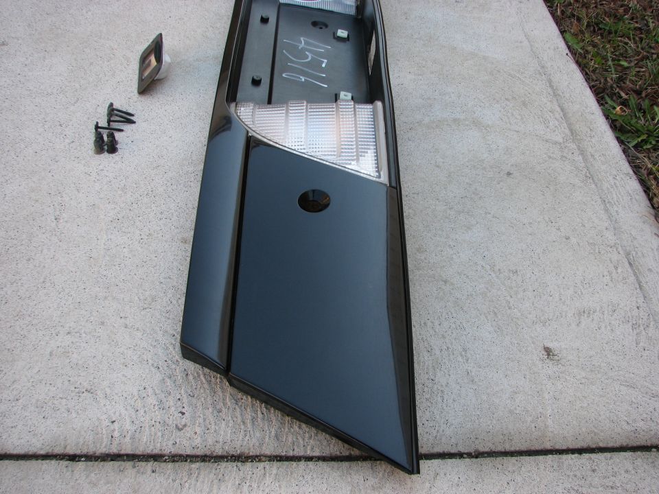 Black car tail light assembly with clear lens section and mounting hardware. Number 4516 is written on the back