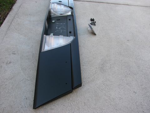 2003 Ford Crown Victoria - A detached car tail light assembly and its hardware are laid out on a concrete surface.
