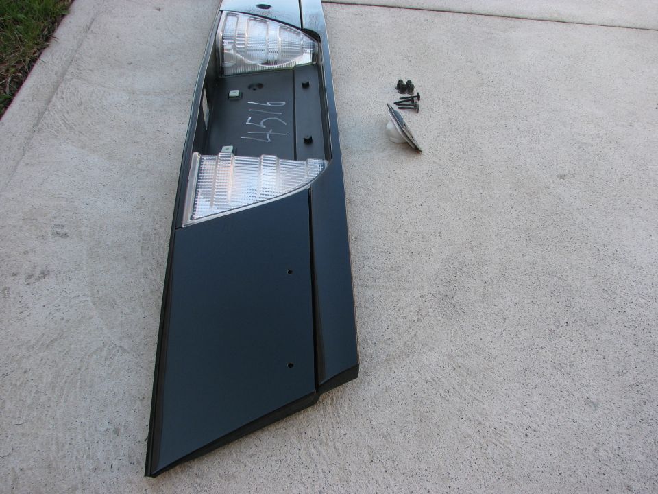Car tail light assembly with screws and a bulb on concrete. Handwritten '4516' on the assembly