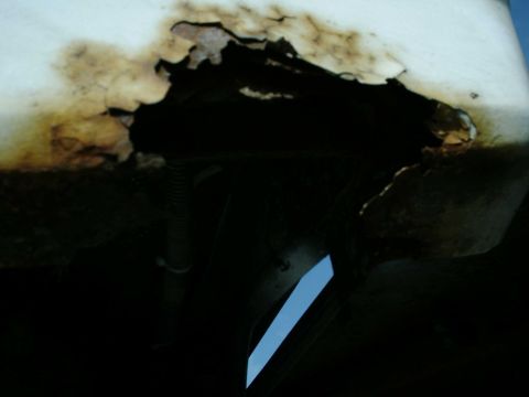 1988 Ford Bronco - The underside of a vehicle shows extensive rust damage and deterioration of the metal body panels.