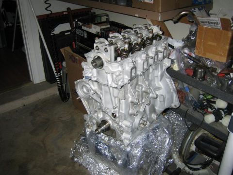 1987 Suzuki Samurai - Engine block with valve train components exposed, resting on protective plastic wrap in a garage setting.