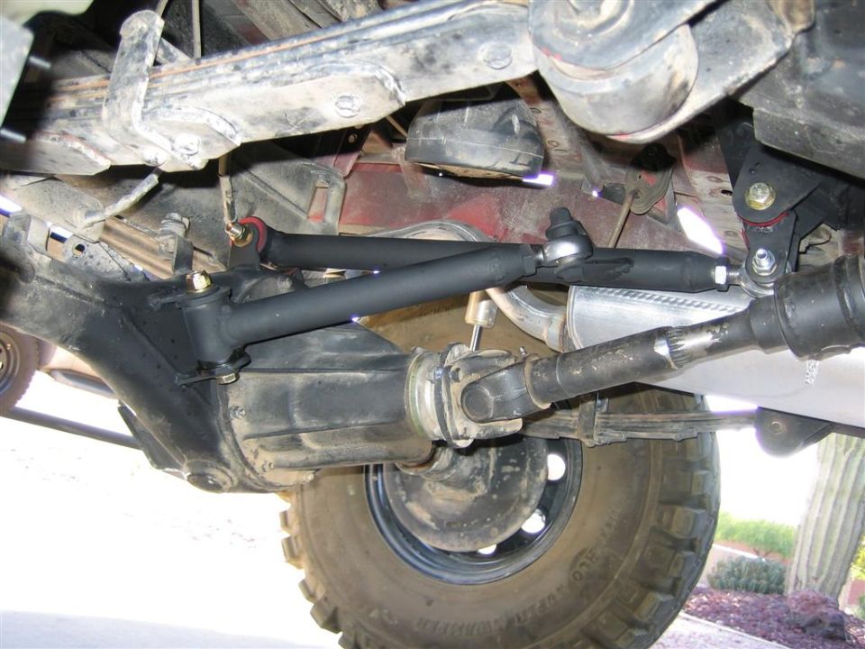 Underside of Samurai front axle showing black steering linkage, differential, driveshaft and off-road tire