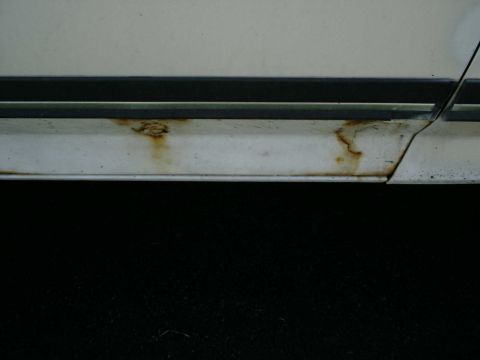 1988 Ford Bronco - Close-up of rust forming on the lower body panel of a vehicle.