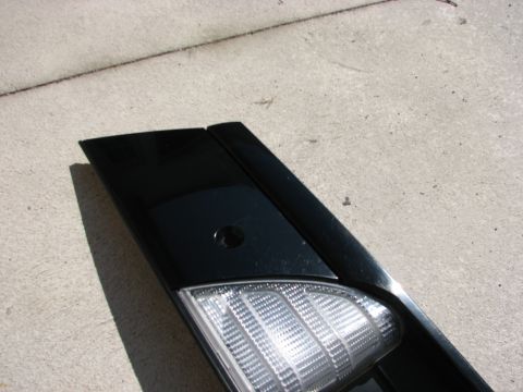 2003 Ford Crown Victoria - A black automotive part with a clear lens is shown close-up against a concrete surface.