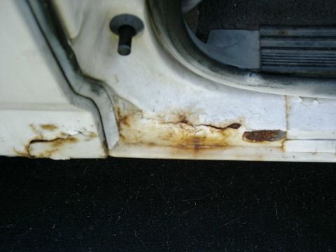 1988 Ford Bronco - Rust damage is visible on the lower part of a vehicle's door frame.
