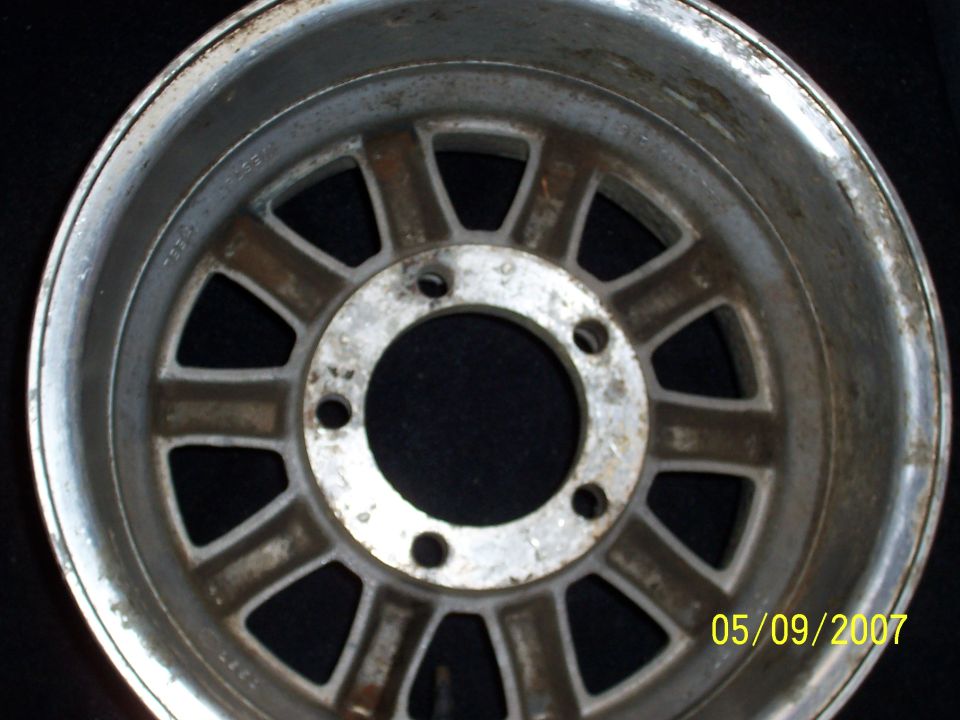 Weathered 10-spoke 6-lug aluminum alloy wheel on dark background