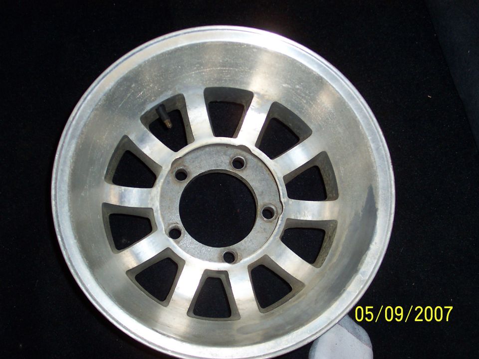 Bare polished aluminum 10-slot alloy wheel with 5-lug pattern on a dark background