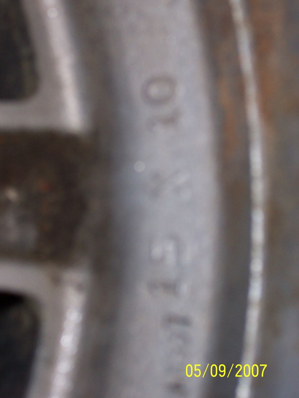 Close-up of stamped numbers on a metal wheel or rim, dated 05/09/2007