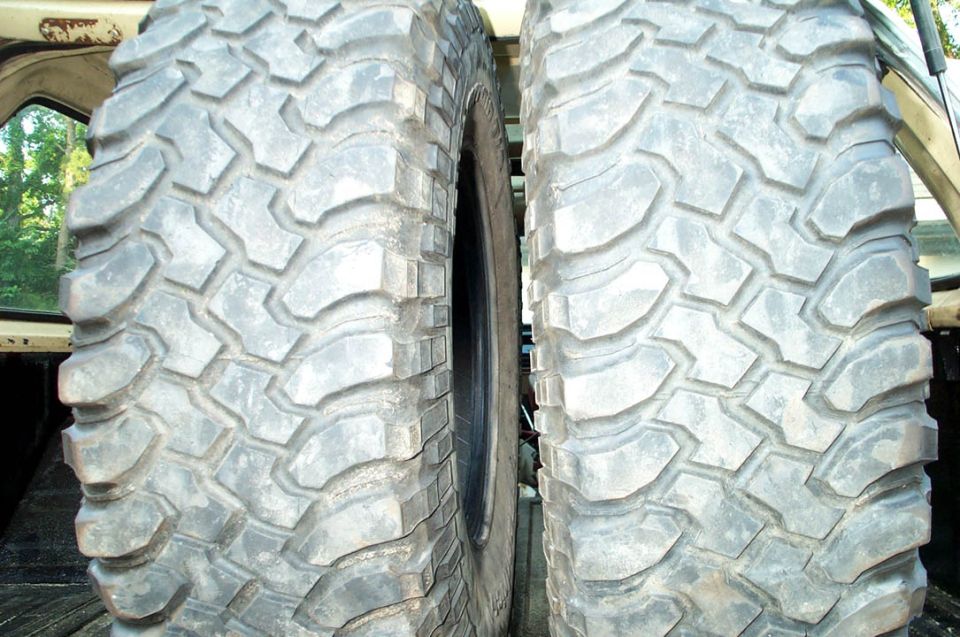Two large off-road tires are side-by-side in the bed of a truck