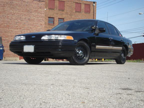 1992 Ford Crown Victoria - A black sedan is parked outside a brick building.