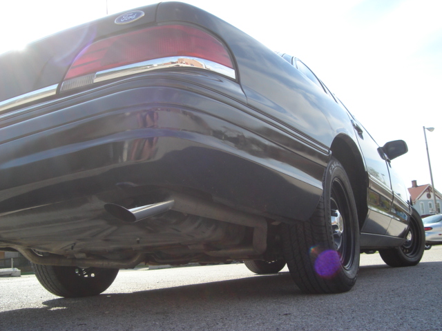 1992 Ford Crown Victoria rear quarter panel, exhaust pipe, and wheel. Black paint