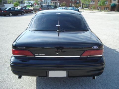 1992 Ford Crown Victoria - This black 1992 Ford Crown Victoria Police Interceptor is parked in a lot with other vehicles visible in the background.