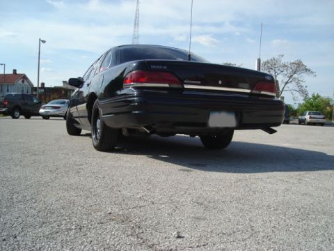1992 Ford Crown Victoria - Rear view of a black 1992 Ford Crown Victoria sedan parked in a lot with other vehicles.
