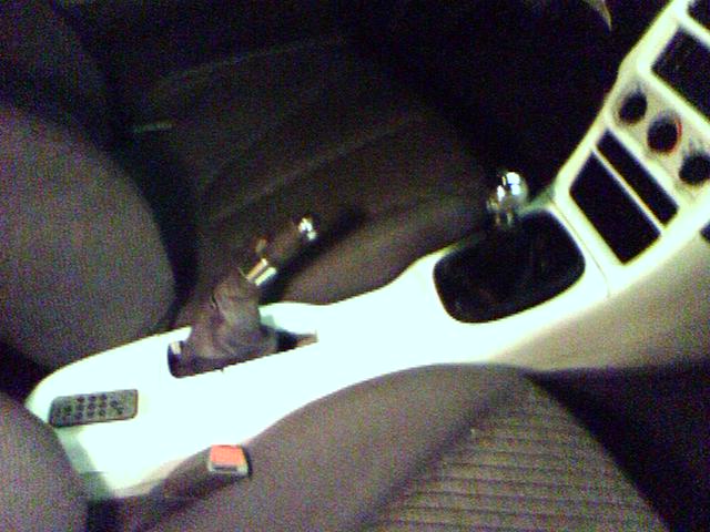 Interior console with gear shifter and buttons, next to car seats