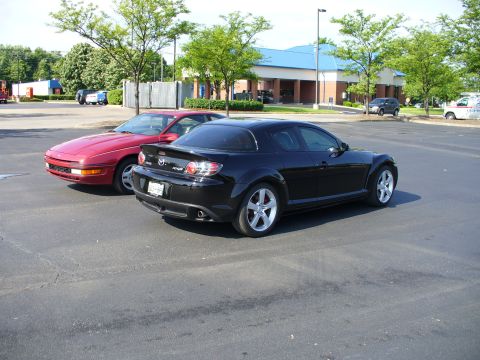 1991 Ford Probe - A black Mazda RX-8 is parked next to a red Mazda MX-6 in a parking lot.