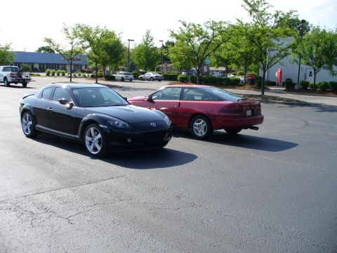 1991 Ford Probe - A red coupe is parked next to a black car in a parking lot.