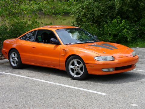 1991 Ford Probe - This orange sports coupe, likely a Mazda MX-6, is shown from the front three-quarter view.