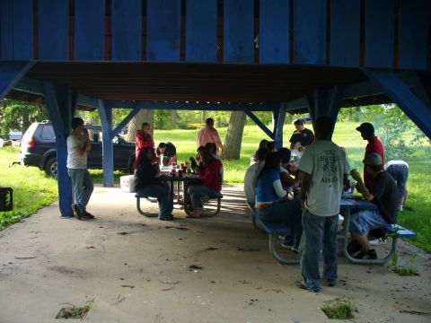 1991 Ford Probe - A group of people are gathered under a blue pavilion at a park, with a black SUV parked nearby.