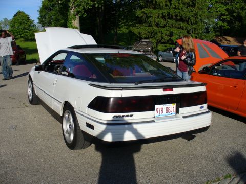 1991 Ford Probe - A white 1991 Ford Probe is parked with its hood open, alongside other vehicles.