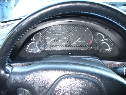 1991 Ford Probe - The interior of a vehicle shows a dashboard with carbon fiber trim and a speedometer and tachometer.