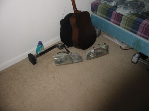 1995 Ford Thunderbird - Car headlights are shown on a carpeted floor next to a guitar and a bed.