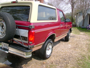 1994 Ford Bronco - This red Ford Bronco is parked outside a building with a gravel driveway.