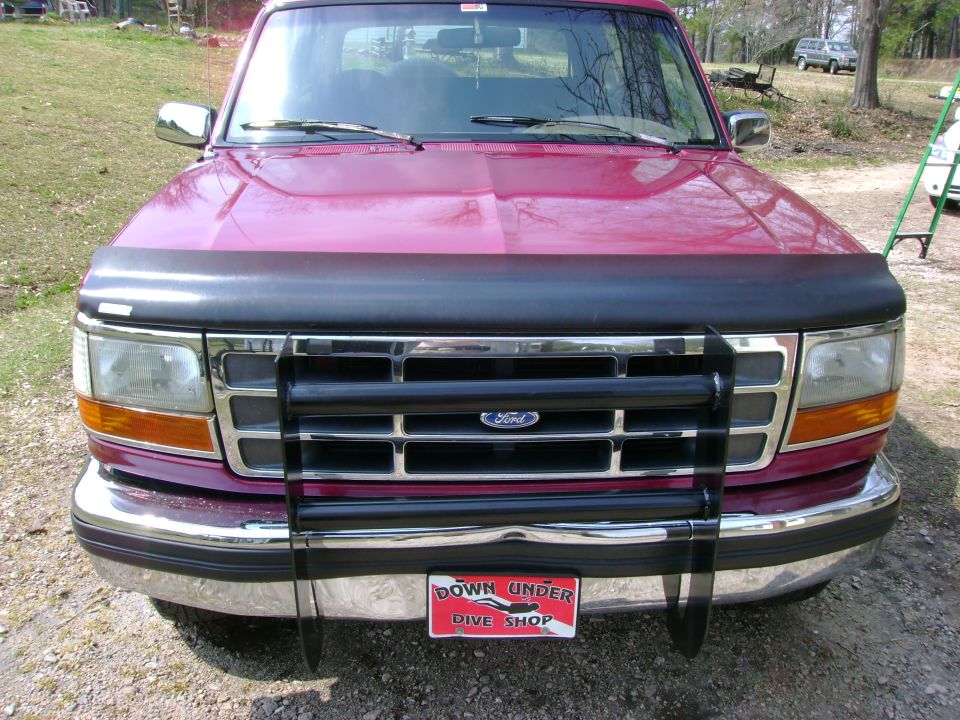 Front view of a maroon Ford F-series truck or Bronco with grille guard and bra