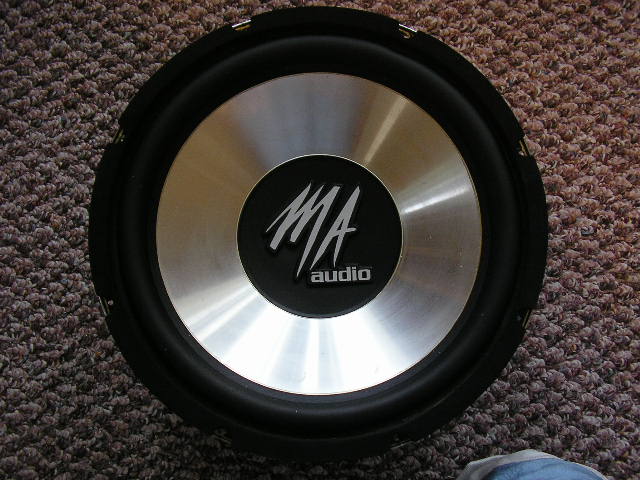MA Audio subwoofer with silver cone and black surround, resting on carpet