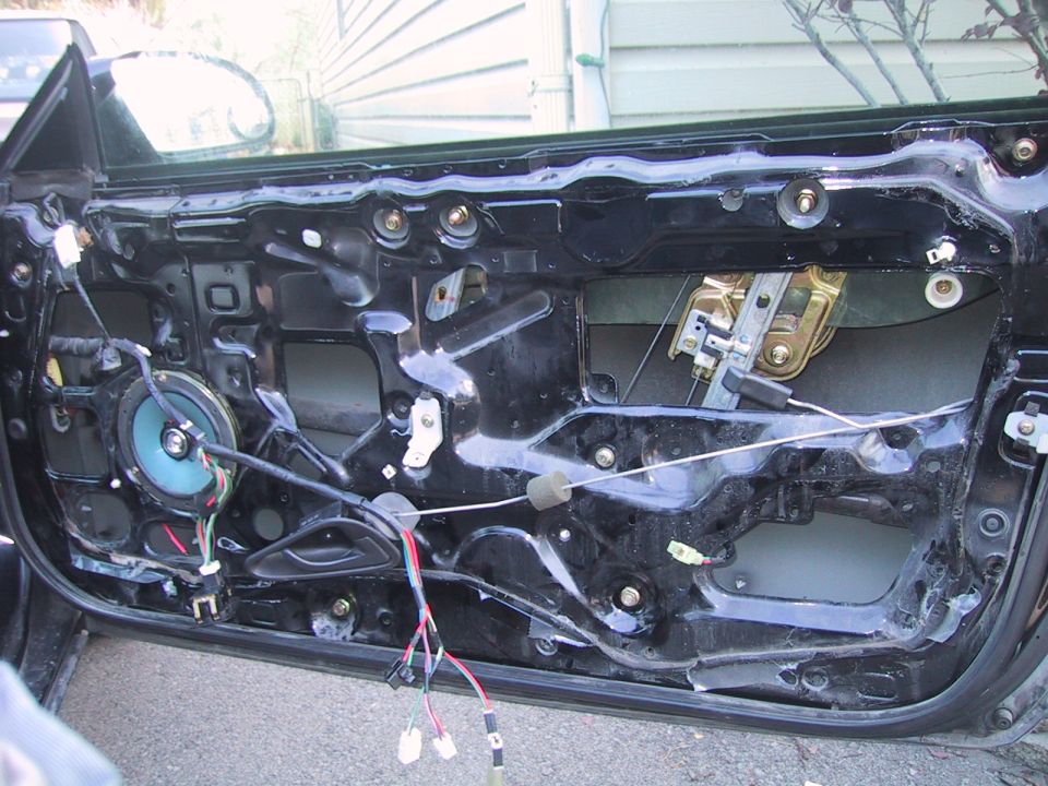 Car door panel removed, showing speaker, window regulator, and wiring