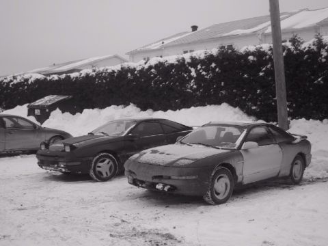 1993 Ford Probe - Two Ford Probes sit in a snowy lot, one with a two-tone paint job.