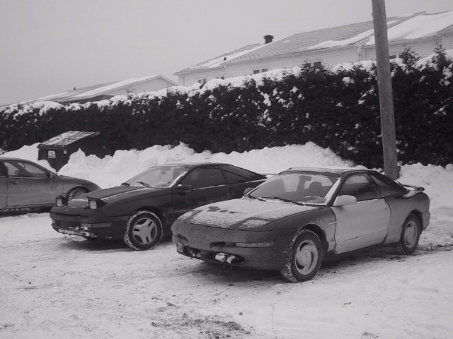 1993 Ford Probe covered in snow, parked outdoors with another car