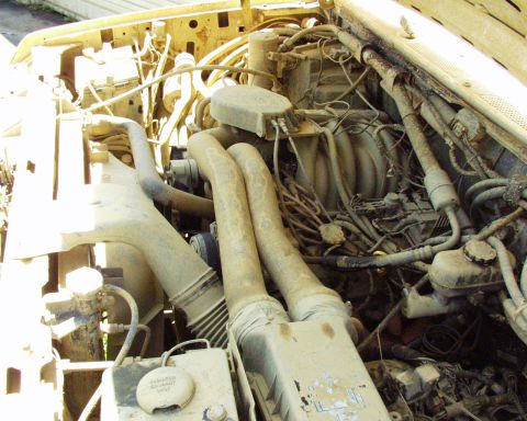 1989 Ford Bronco - The engine bay of a vehicle, covered in dust and grime, showing various mechanical parts.