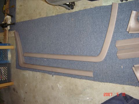 1993 Ford Bronco - Tan interior trim pieces are laid out on a blue carpeted floor.