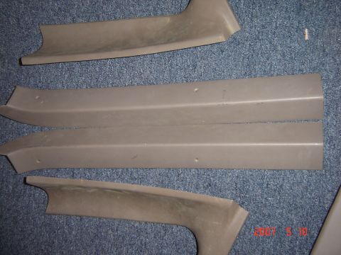 1993 Ford Bronco - Tan plastic interior trim pieces are shown on a carpeted surface.