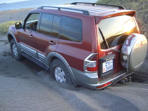 1974 Ford Bronco - Mitsubishi Pajero stuck in sand, with the ocean in the background.