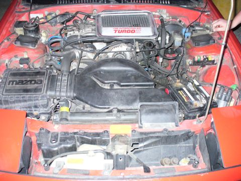 1991 Ford Probe - The engine bay of a red Mazda features a 13B Intercooled Turbo II engine with prominent Mazda branding on the air intake box.