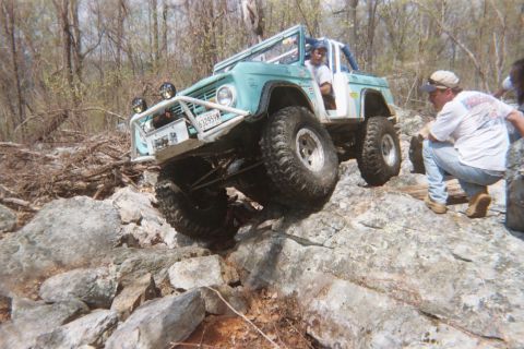 1969 Ford Bronco - A modified 1966 Ford Bronco tackles a challenging rock crawling course with two people visible.