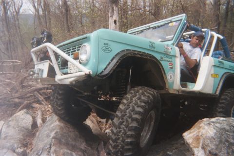 1969 Ford Bronco - This 1969 Ford Bronco is equipped for extreme off-roading, navigating a rocky trail with significant suspension modifications.