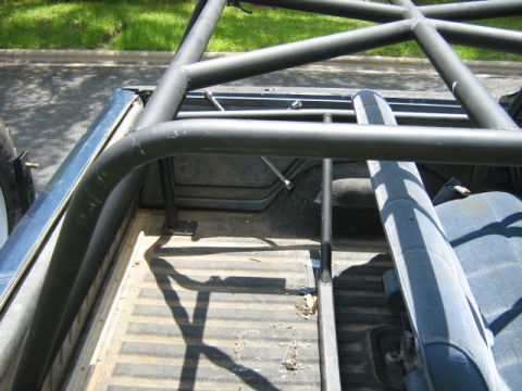 1986 Ford Bronco - Interior view of a truck bed with a custom roll cage and blue seats.
