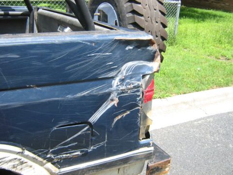1986 Ford Bronco - The rear quarter panel of a blue 1986 Ford Bronco shows extensive damage and numerous scratches, indicating a rough history.