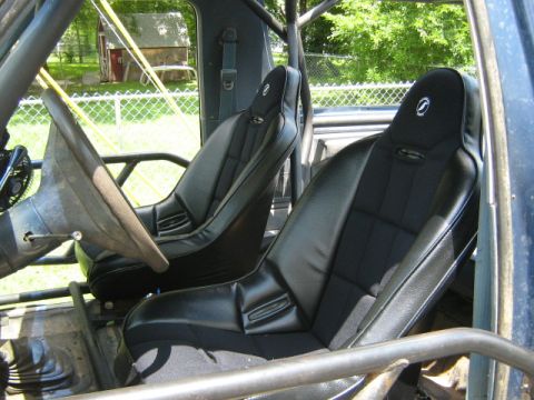 1986 Ford Bronco - Custom interior with racing seats and a roll cage, seen from the passenger side.