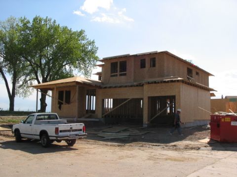 1995 Ford Bronco - A white pickup truck is parked on a dirt road in front of a house that is currently under construction.